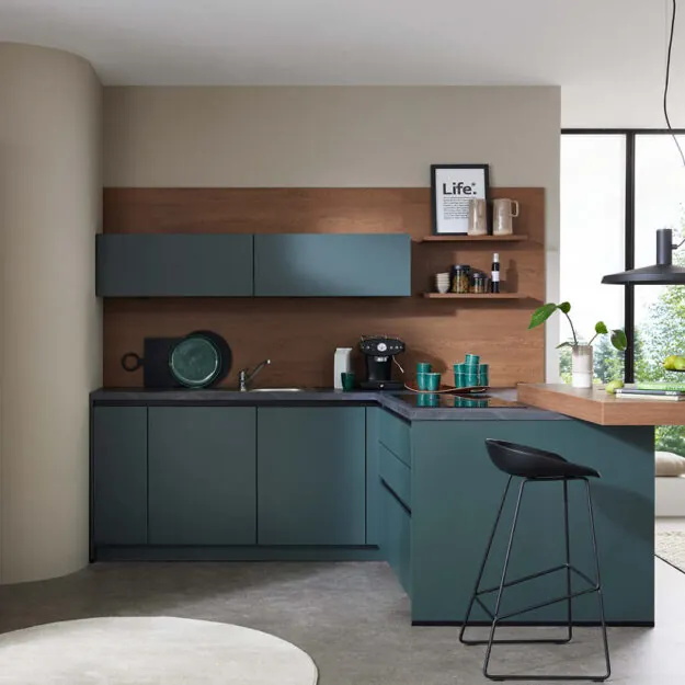 Moderne Burger Küche bei Küchenstudio Depping mit grünen Fronten, Holzrückwand und L-förmiger Küchenlösung mit Thekenbereich und Barhocker